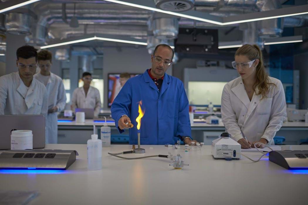 Laboratory environment - one male is using a bunsen burner while others are watching