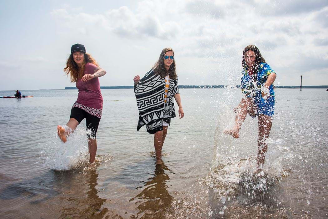 3 students laughing and paddling in the sea