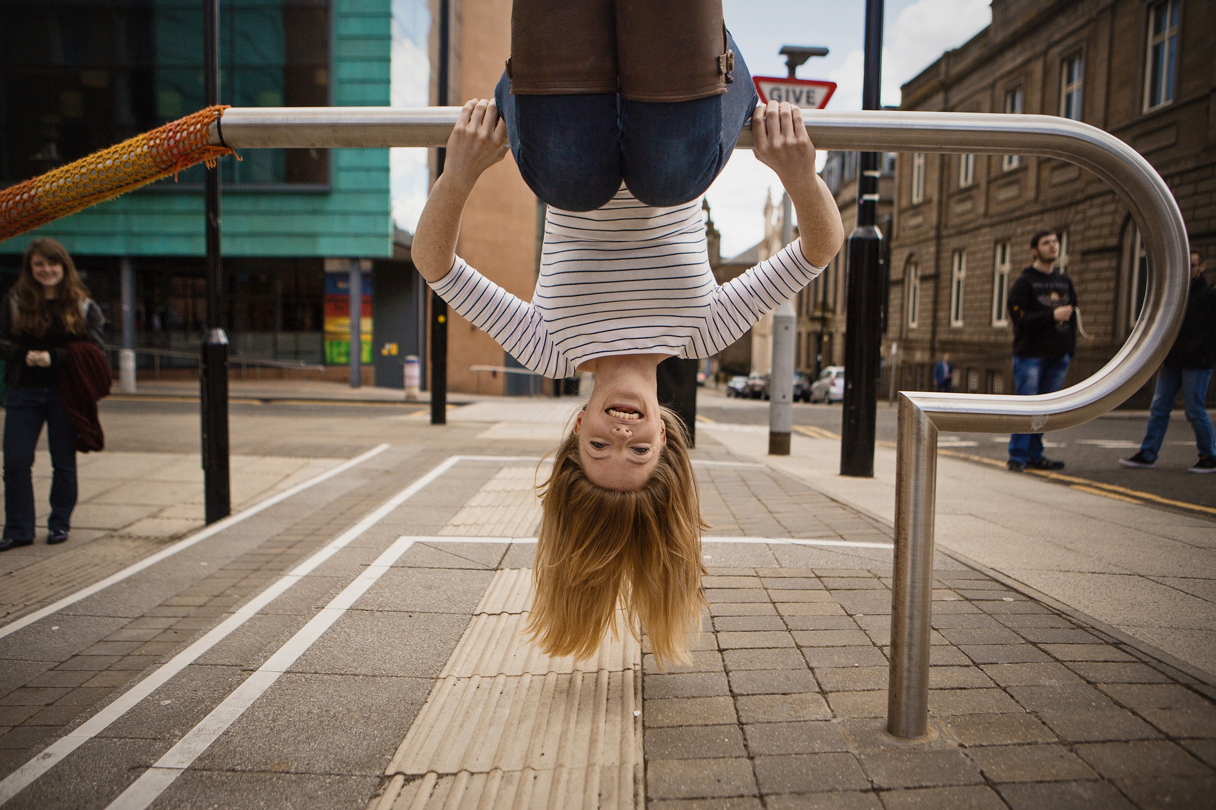 Female hanging upside down on hand railing