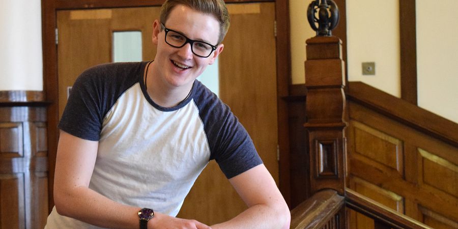 Smiling male leaning against a hand banister
