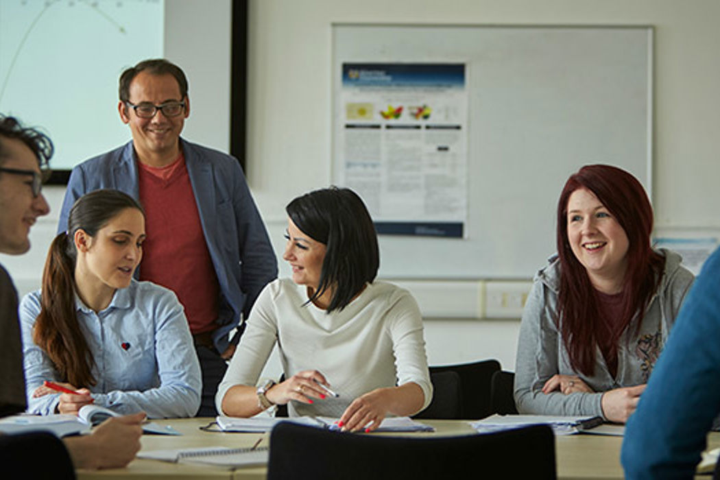 Students working together in a seminar room with a lecturer present, highlighting the collaborative and supportive learning environment at the university.