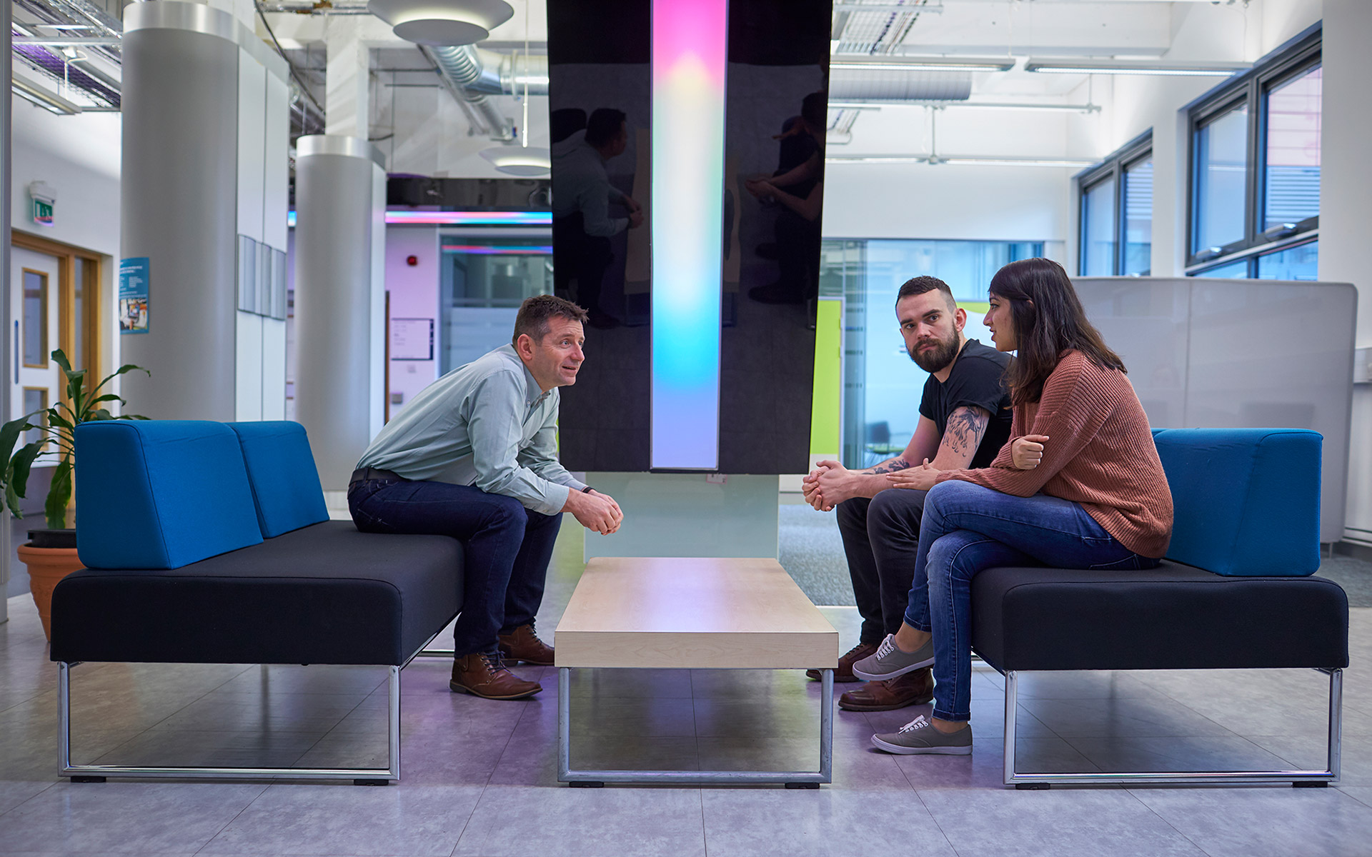 Three people sitting on sofas talking