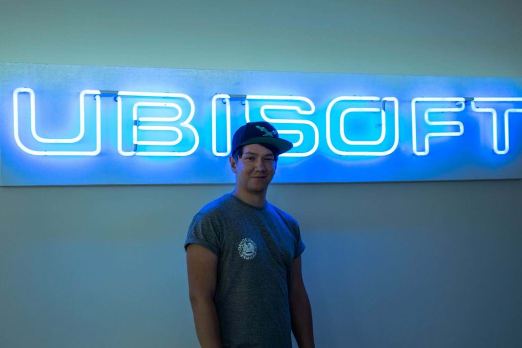 Male wearing a baseball cap standing in front of a Ubisoft sign