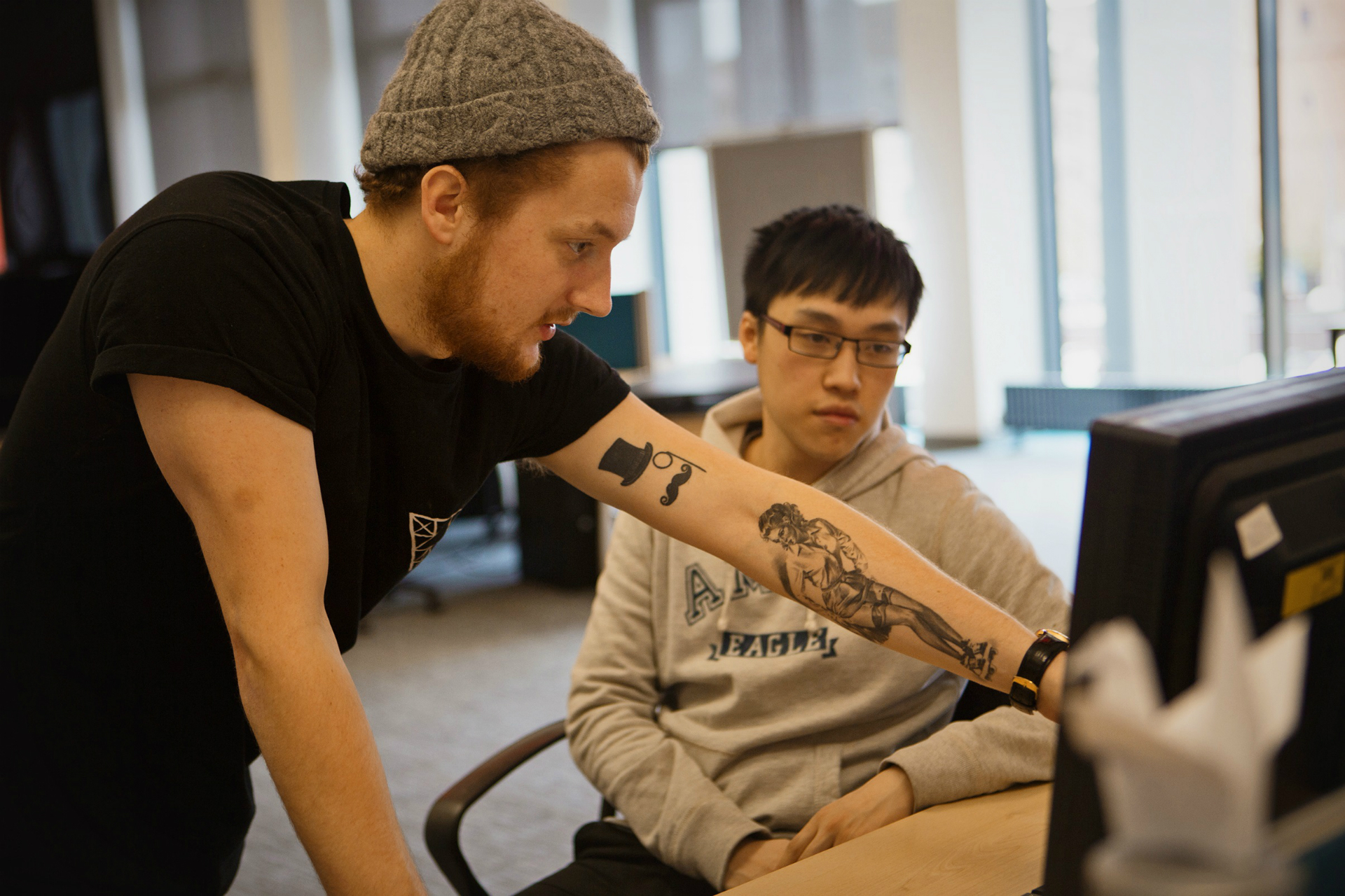 Two males working together on a Desktop computer