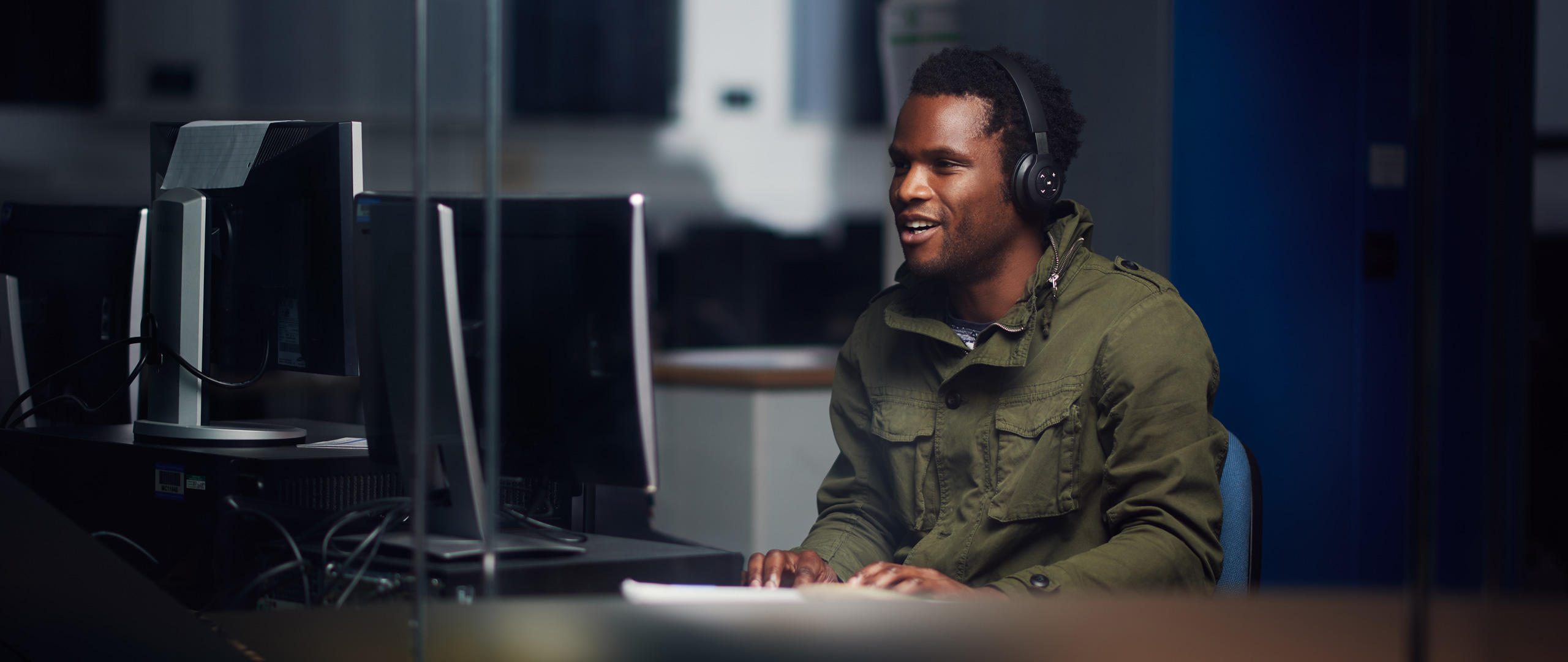 Male wearing headphones and using a Desktop computer