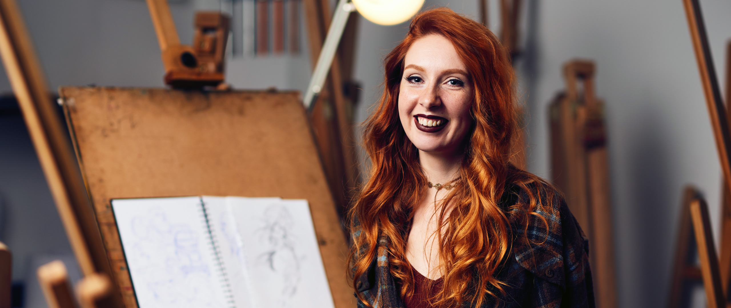 smiling female standing in front of an art easel