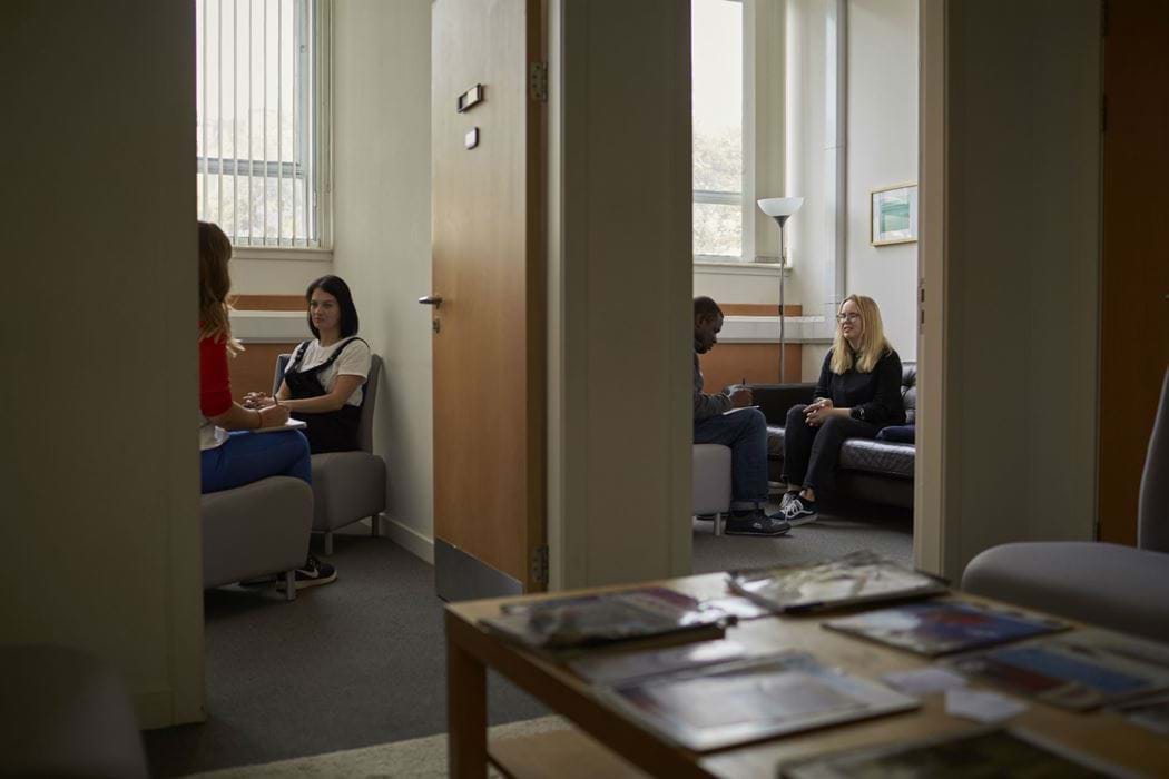 Two rooms - room 1 shows a female counselling another female. room 2 shows a male counselling a female