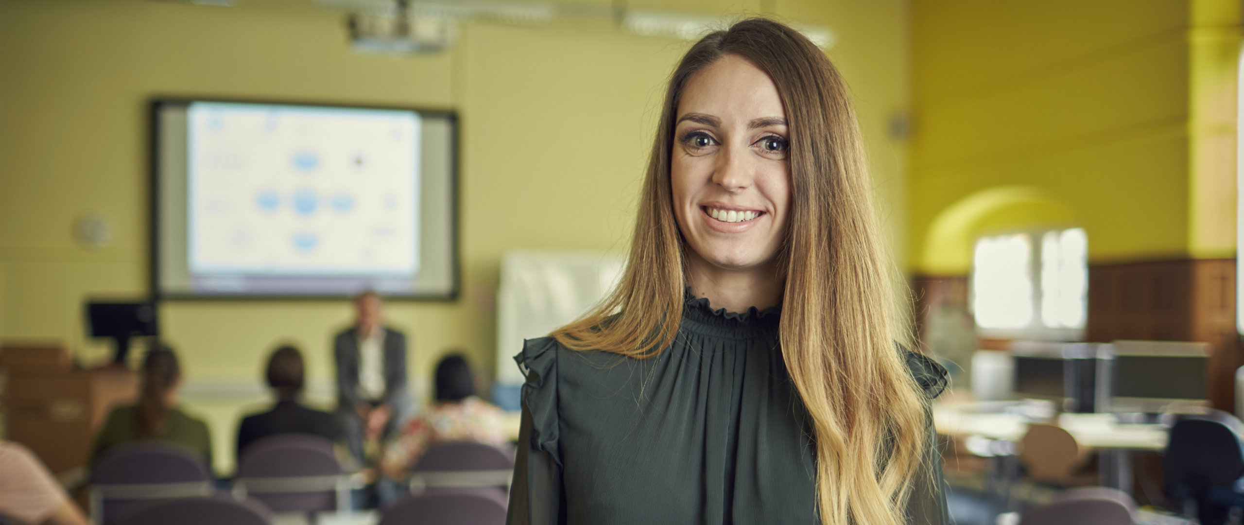 Smiling female with class of students in the background