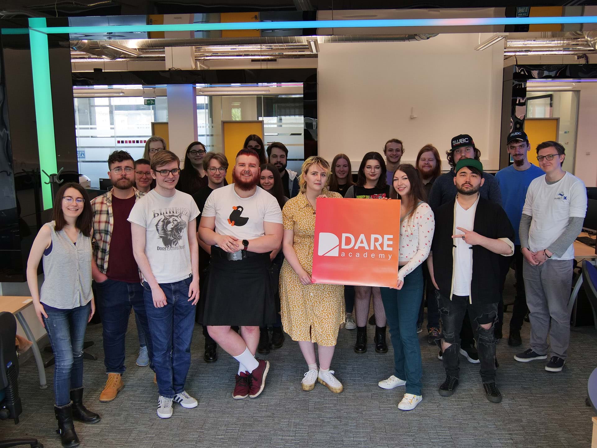 The image shows a group of students in a computer lab holding a Dare Academy sign