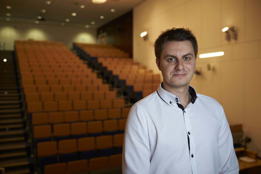 Christopher Watkins standing in front of an empty lecture theatre