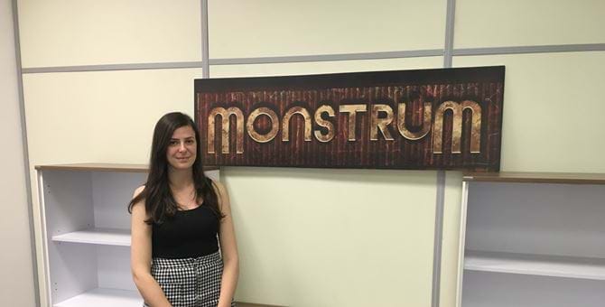 A picture of Stephanie Bayzeley by the logo for the game Monstrum