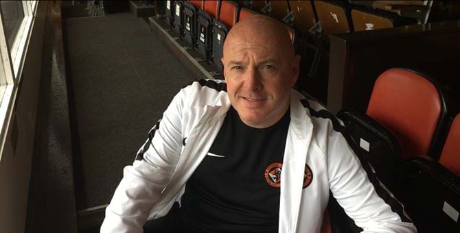 A photo of Joe Rice sitting in the stands at Tannadice