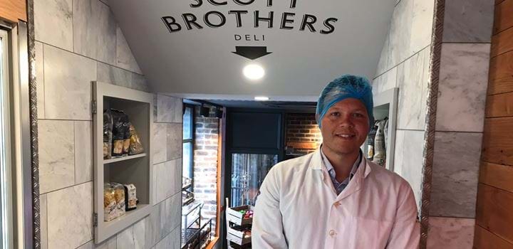 A picture of Samuel Ceolin wearing a hairnet and apron at Scott Brothers Butcher