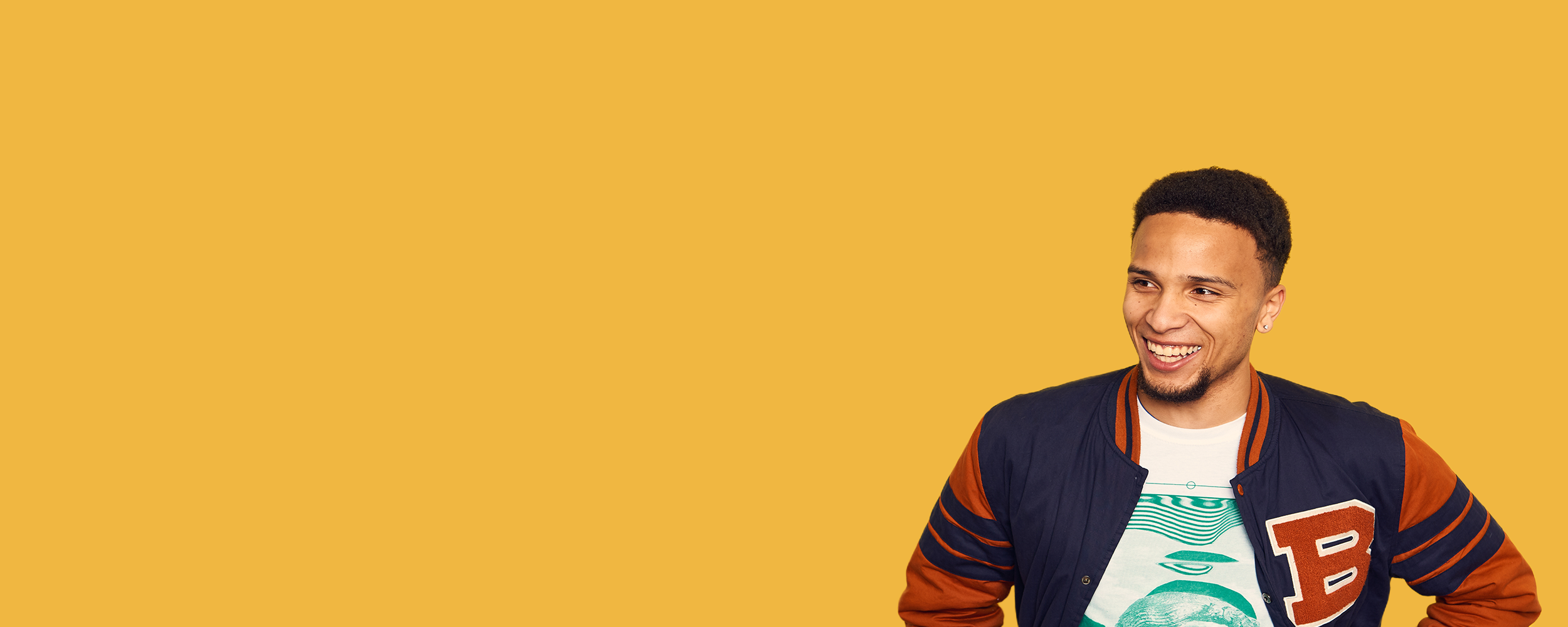 Graduate on mustard yellow background smiling