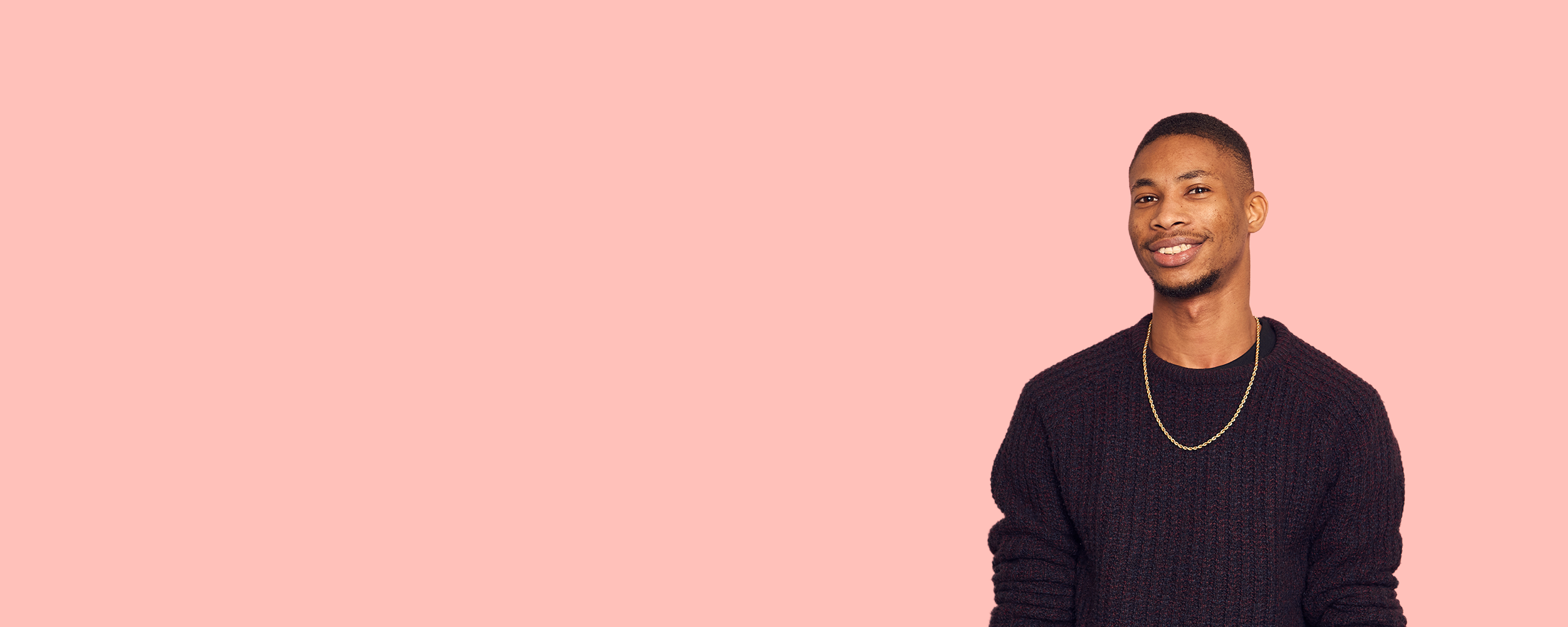 Grad standing against a pink background smiling