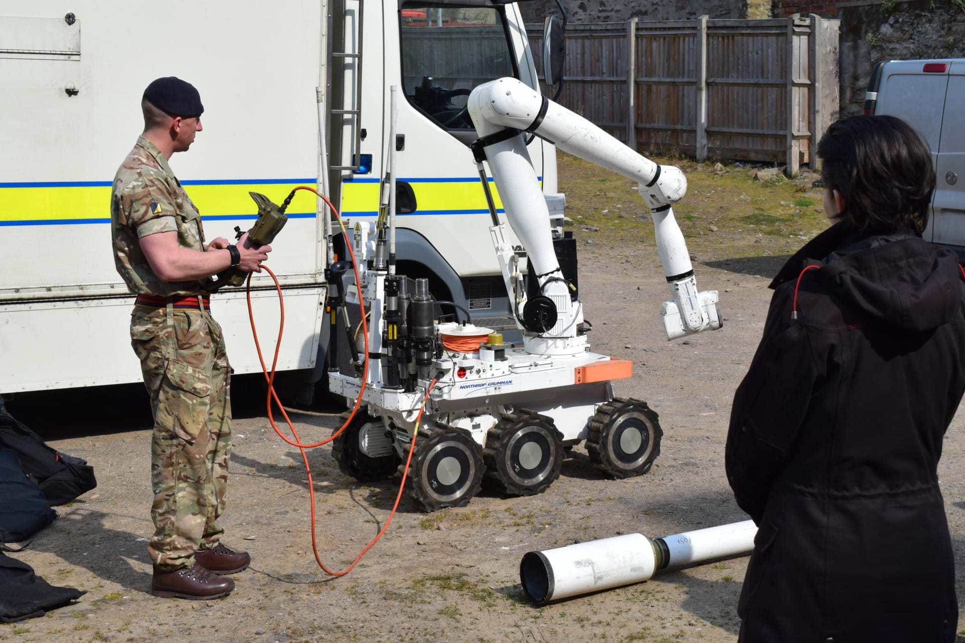 A member of the bomb disposal unit using the bomb disposal robot in front of students