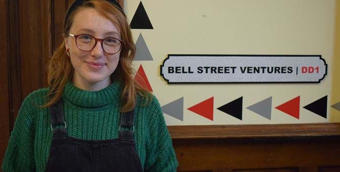 A picture of Stephanie Crowe standing in front of a sign with the words "Bell Street Ventures" on it.