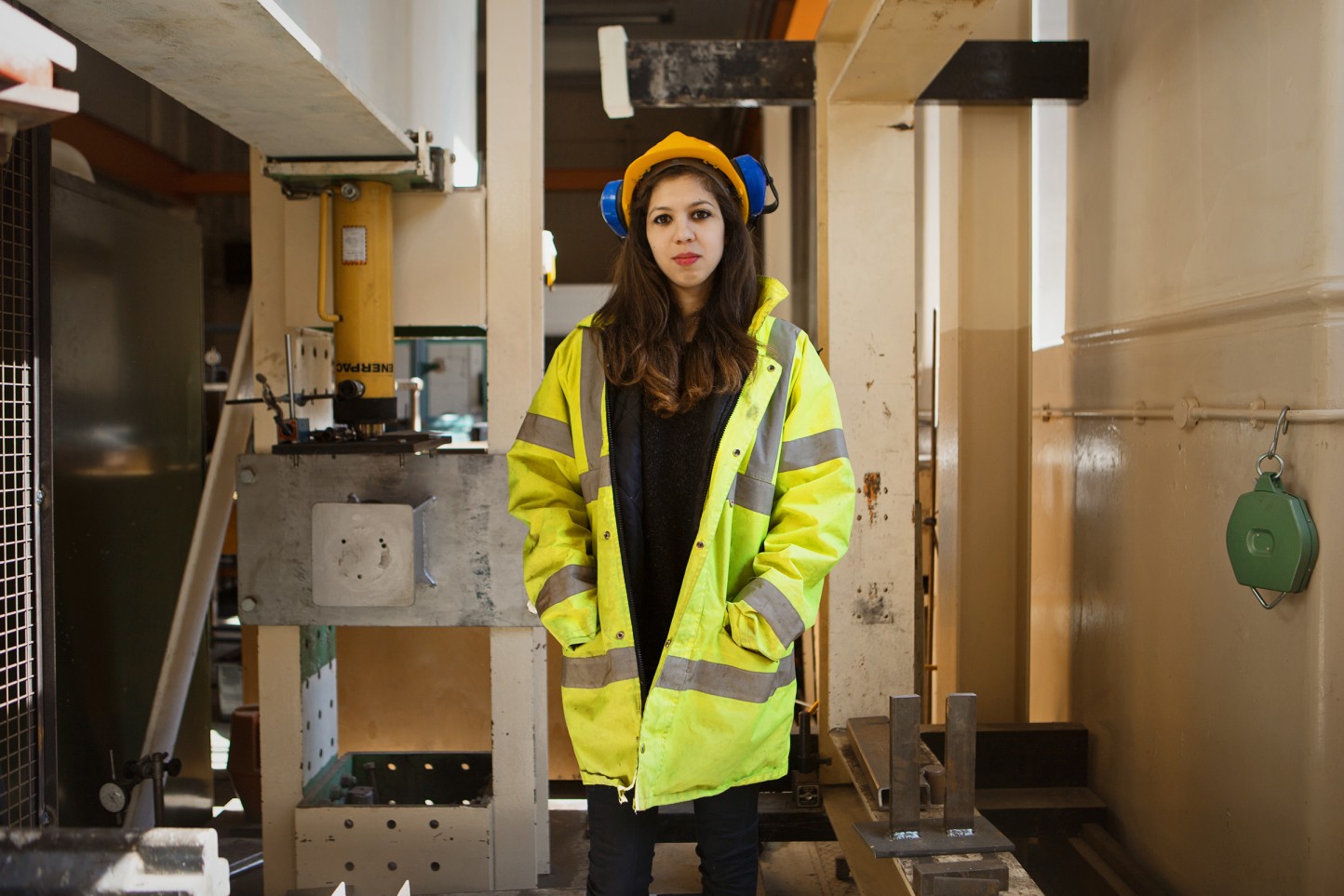 Woman engineer wearing safety equipment - goggles, helmet and two wrenches