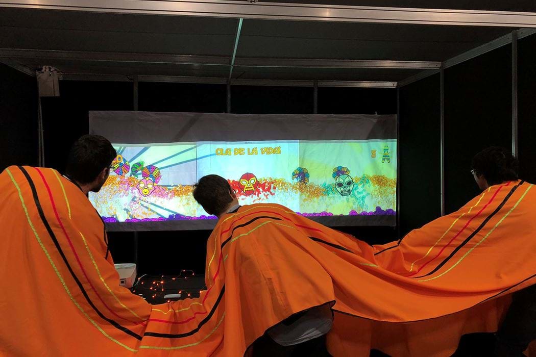 Three students in a three-person poncho playing an interactive game 
