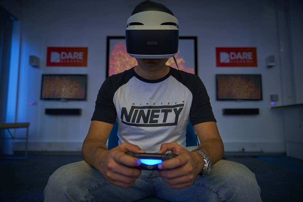 Abertay University Student in a PSVR helmet facing the camera holding a PS4 Controller