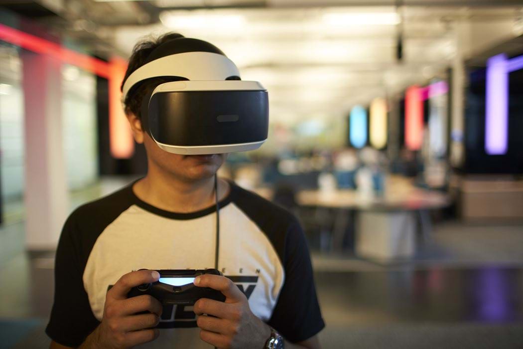 Abertay University Student in a PSVR helmet facing the camera holding a PS4 Controller
