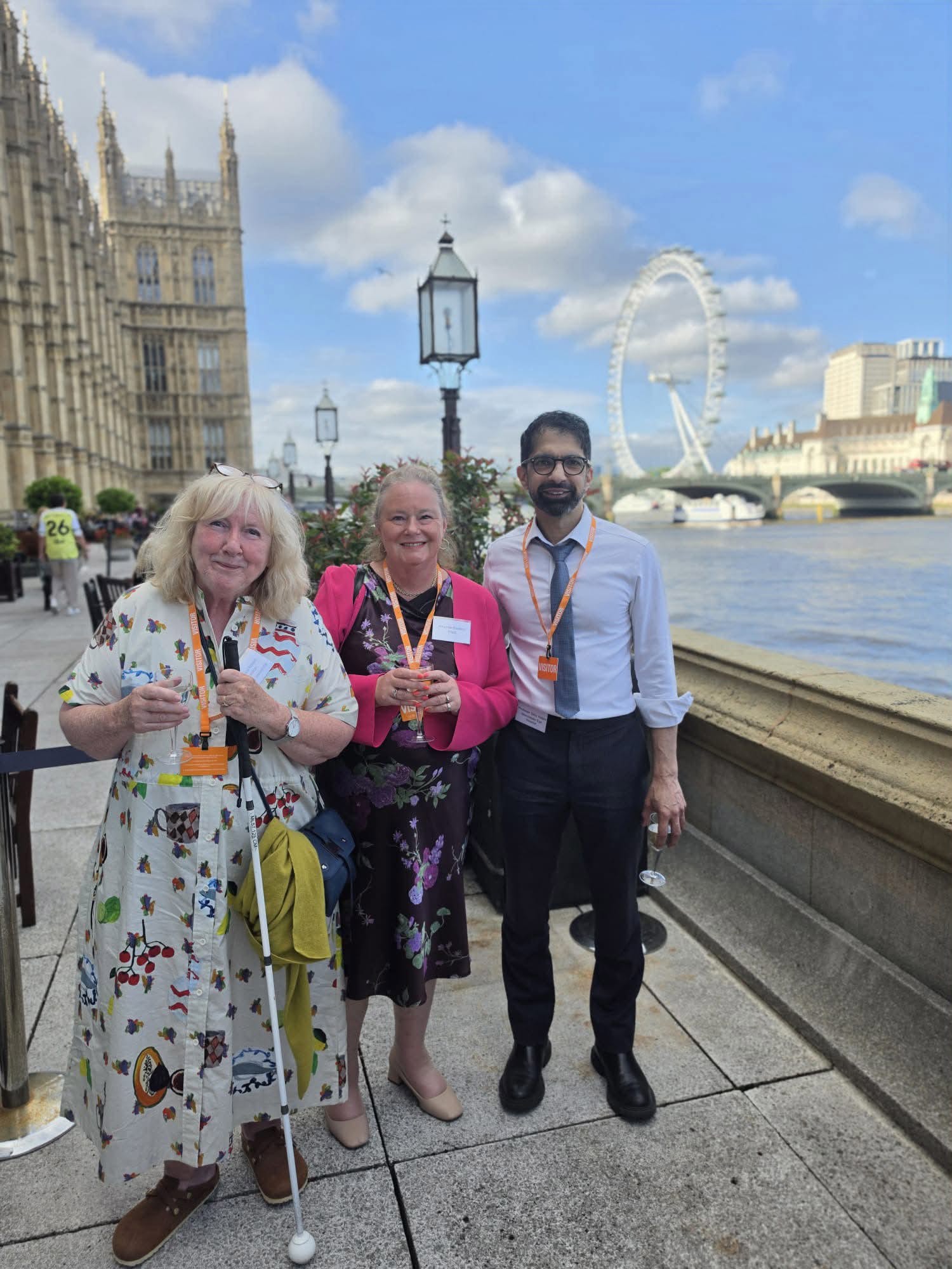 Photo shows (left to right) Prof Mhairi Thurston with Amanda Hawkins (RNIB) and Professor Tariq Aslam (Lead Ophthalmologist) on the Thames Pavilion at Westminster. They smile and look to the camera on a bright day outside the Houses of Parliament on the banks of the River Thames.
