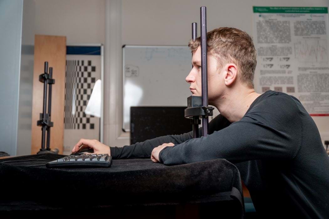 Male student carrying out an eye tracking experiment in psychology lab.
