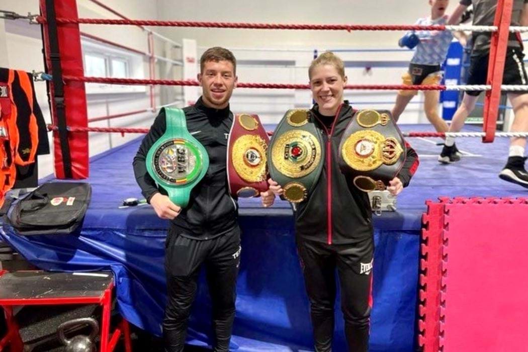 On the left Dean Sutherland holding the World Boxing Council silver title. On the right, Hannah Rankin holding the International Boxing Organisation titles