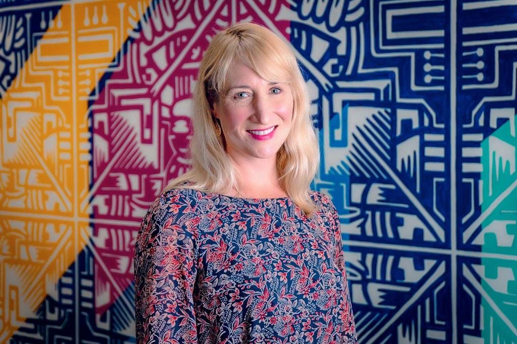 Beth Meehan standing in front of a colourful background.